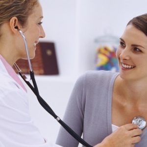 Side profile of a female doctor examining a young woman's chest with a stethoscope